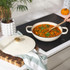 Cream cast iron casserole dish with lid, shown on hob with stew cooking