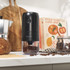Black cordless electric coffee grinder with clear container, cleaning brush and USB charging cable.