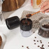 Black cordless electric coffee grinder with clear container, cleaning brush and USB charging cable.