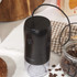 Black electric coffee grinder with clear container, USB charging cable and cleaning brush