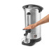 Hand dispensing hot water into a glass cup from a silver catering urn