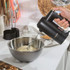 Black and gold electric hand mixer with metal beaters, side profile
