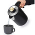 Black and gold electric kettle pouring hot water into a grey mug