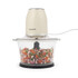 Cream electric food chopper with glass bowl, filled with chopped vegetables