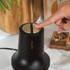 Hand pressing button on black and gold Salter electric grinder in kitchen setting