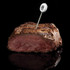 Digital meat thermometer inserted in medium-rare steak, showing temperature on display