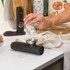 Black electronic salt and pepper grinder set with charging base, angled view