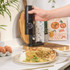 Black electronic salt and pepper grinder set with charging base, angled view