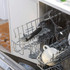 Open dishwasher rack with mugs and wine glasses inside