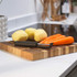 Vegetable peeler with peeled potatoes and carrots on wooden chopping board