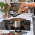 Black handled flat cheese grater with stainless steel blade, angled on white background