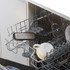 Black metal grater on top rack of dishwasher with mugs and wine glasses