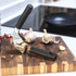 Stainless steel garlic press with black handles, shown closed on white background