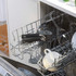 Open dishwasher with cups, plates, and wine glasses in top rack