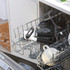 Black can opener with soft grip handles in dishwasher upper rack, next to cups and glasses