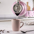 Pink kettle pouring hot water into matching mug on kitchen counter