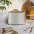 2-slice stone-coloured toaster with gold controls, side view