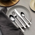 Four-piece stainless steel cutlery set on grey plate, showing fork, knife, tablespoon and teaspoon.