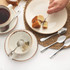 Table setting with cake, tea, ceramic crockery and stainless steel teaspoons.