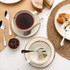Table setting with cake, tea, ceramic crockery and stainless steel teaspoons.