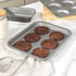 Non-stick baking tray with six chocolate cookies in kitchen setting