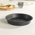 Round grey non-stick pizza tray with speckled finish on kitchen worktop