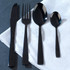 Set of four black stainless steel cutlery pieces on white napkin