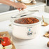 Cream Salter slow cooker with lid being lifted, showing cooked stew inside