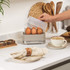 Taupe electric egg cooker showing cooked egg in poacher tray with lid being lifted
