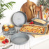 Set of grey non-stick bakeware trays with cakes and pastries, shown in a kitchen.