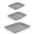 Set of three non-stick baking trays in different sizes, silver, angled view.