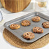 Non-stick baking tray with six cinnamon swirls, shown on kitchen worktop