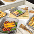 Non-stick roasting trays with grilled vegetables and whole roast chicken on kitchen counter