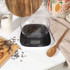 Digital kitchen scale with clear bowl on countertop, cookies and utensils beside.