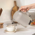 Taupe electric kettle pouring water into cup, shown in modern kitchen setting