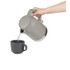 Taupe cordless electric kettle pouring hot water into grey mug, shown in use