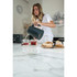 Grey electric kettle pouring hot water into tea mugs beside fresh bread on kitchen counter