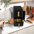 Hand removing black and gold air fryer drawer, basket shown extended from appliance