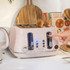 Pink four-slice toaster with heated bagels, shown in a modern kitchen setting.