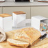 Set of three white kitchen canisters with wood lids, shown with sliced bread and tea bags.
