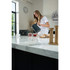 Modern grey electric kettle pouring hot water into glass mug on marble kitchen counter