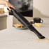Handheld cordless vacuum cleaning crumbs from kitchen worktop, shown in use.