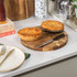 Two golden brown pies on a wooden board with a knife, shown on a kitchen counter.