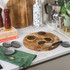 Three chocolate tarts on wooden board, one sliced open, next to tart tins and knife.