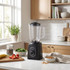 Black countertop blender in modern kitchen with fruit and breakfast ingredients