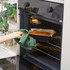 Tray of cooked food being taken from oven with green cloth