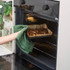 Brownie tray being removed from oven with green tea towel