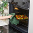 Hand placing tray of sliced vegetables into oven