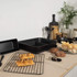 Set of black non-stick bakeware with cooling rack and kitchen tools on worktop