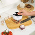 Manual food chopper with hands adding tomato, for dicing vegetables at home.